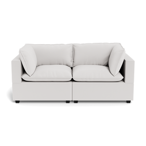 The Kova Pillow Cushion Sofa 86" is a modern, light gray two-seater with square arms and four matching cushions, shown from the front against a black background.