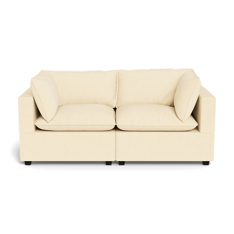 The Kova Pillow Cushion Sofa 86" is a beige, modern two-seater with plush seat and back cushions plus two matching side pillows, displayed against a black background.