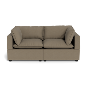 The Kova Pillow Cushion Sofa 86" features a modern, boxy design with light brown upholstery, two seat cushions, two back cushions, and two matching side pillows—displayed against a plain black background.