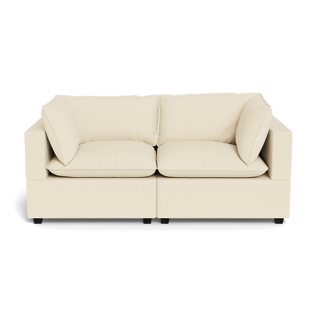 The Kova Pillow Cushion Sofa 86" is a modern, light beige sofa with two seat and back cushions and wide square arms, shown from the front against a plain black background.