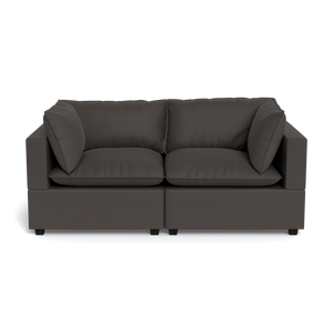 The Kova Pillow Cushion Sofa 86" is a modern, dark gray two-seater with clean lines and four matching cushions, shown from the front against a black background.