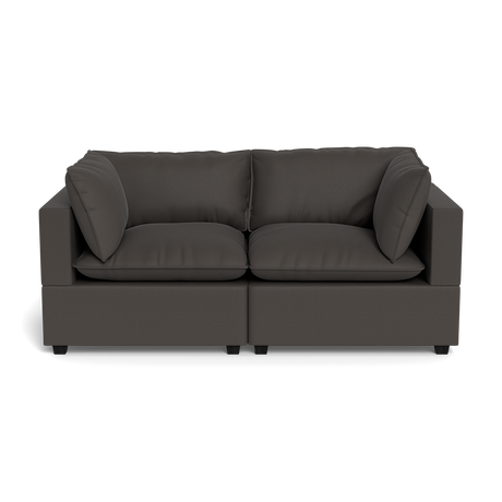The Kova Pillow Cushion Sofa 86" is a modern, dark gray two-seater with clean lines and four matching cushions, shown from the front against a black background.