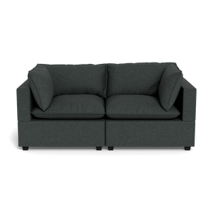 The Kova Pillow Cushion Sofa 86" is a modern dark grey two-seater with square arms and four matching cushions, displayed against a plain black background.