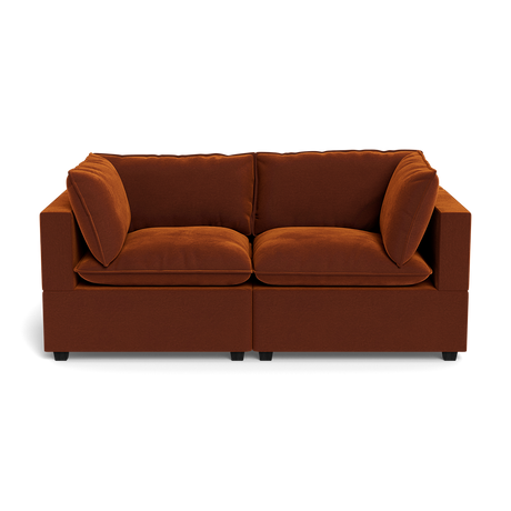The Kova Pillow Cushion Sofa 86" is a modern dark orange velvet sofa with two seat and two back cushions, pictured from the front against a black background.