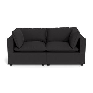 The Kova Pillow Cushion Sofa 86" is a modern dark gray sofa with two seat cushions and two matching side pillows, shown from the front against a plain black background.