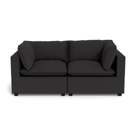 The Kova Pillow Cushion Sofa 86" is a modern dark gray sofa with two seat cushions and two matching side pillows, shown from the front against a plain black background.