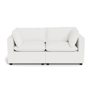 The Kova Pillow Cushion Sofa 86" is a modern white two-seater with square arms and four cushions, displayed against a plain black background.