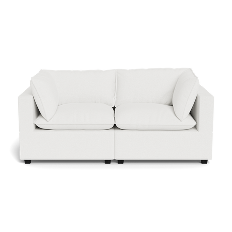 The Kova Pillow Cushion Sofa 86" is a modern white two-seater with square arms and four cushions, displayed against a plain black background.