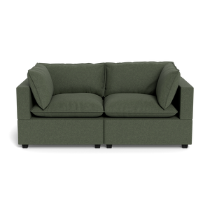 The Kova Pillow Cushion Sofa 86" is a modern dark green fabric sofa with thick seat and back cushions, two large side pillows, and square armrests, shown from the front against a black background.