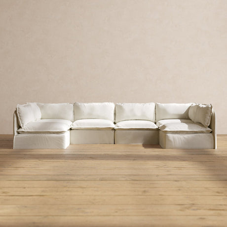 A spacious and modern Modular Performance 6-Seater Open-Ends U-Sectional in Plush Weave Ash with plush white cushions is placed against a neutral-toned wall. Complementing the wooden floor, this sectional adds to the minimalist design of the room, creating an inviting and open atmosphere.