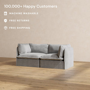 A minimalist, sunlit room with a wooden floor showcases a light gray Modular Performance 2-Seater with Sink-in Comfort Cushion. Text highlights include "100,000+ Happy Customers," "Machine Washable," "Free Returns," and "Free Shipping.