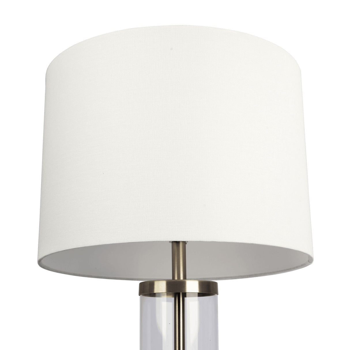 The Luna Table Lamp features a transparent cylindrical base with a metallic rim, white cylindrical lampshade, and an on/off switch, offering sleek and minimalist design perfect for contemporary interiors.
