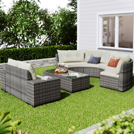 An 8-piece outdoor wicker round sofa set, including a half-moon sectional with cream cushions and decorative pillows, is arranged on a grassy area near a white house with large windows. The set features a rectangular glass-top coffee table and is surrounded by lush green bushes.
