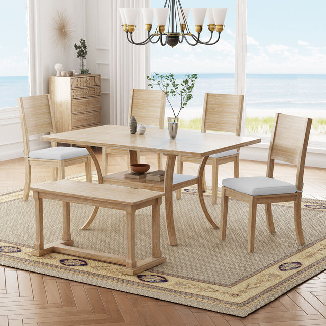 A dining room featuring the Topmax 6 Piece Wood Dining Table Set with a table, bench, and four cushioned chairs on a patterned rug. A sideboard with decor lines the wall, while a chandelier hangs above. Large windows frame a beach view.