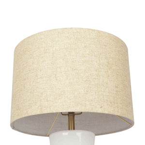 The Cascade table lamp features a beige fabric lampshade in a simple cylindrical design, set on a white bulb holder with a brass-like support structure, all against a plain white background.