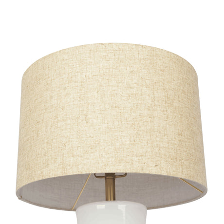 The Cascade table lamp features a beige fabric lampshade in a simple cylindrical design, set on a white bulb holder with a brass-like support structure, all against a plain white background.