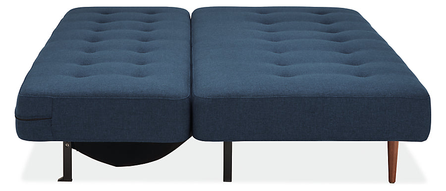 The Deco Convertible Sleeper Sofa in blue fabric, fully extended with a tufted surface, featuring wooden and metal legs on a white background.