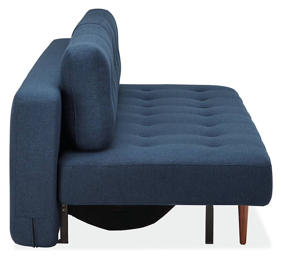 Side view of the Deco Convertible Sleeper Sofa in modern blue, showcasing a tufted seat and backrest. It features wooden legs and a sleek design, perfect for a minimalist room setting.