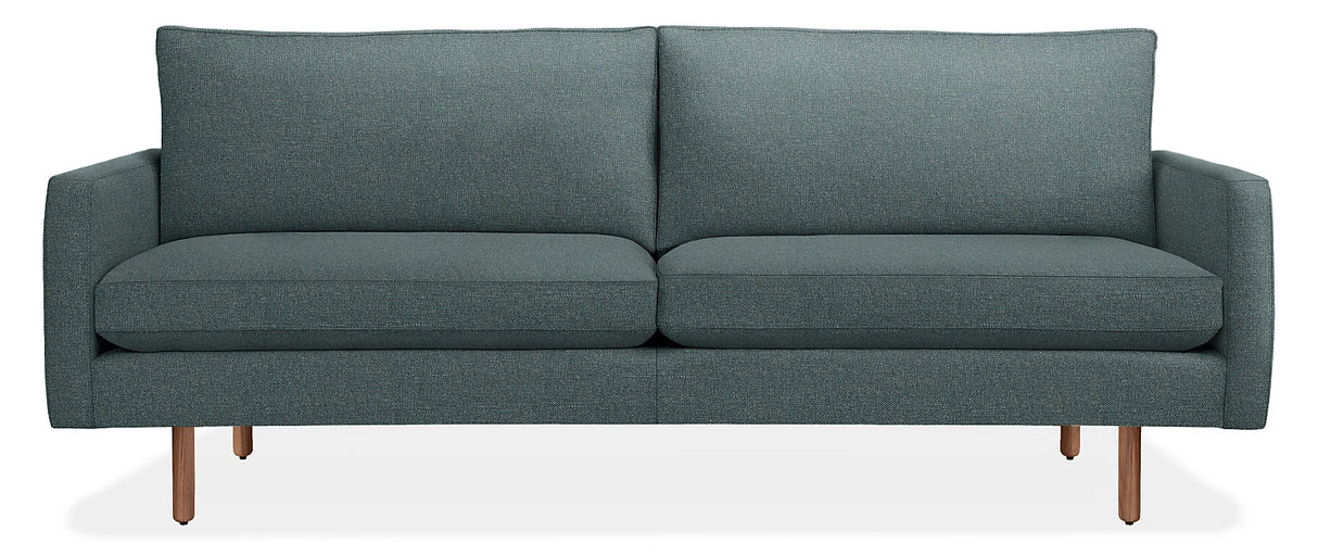 The 86" Jasper Sofa is a modern, teal two-seater with clean lines and a minimalist design. It features plush cushions and slim wooden legs, all set against a plain white background.