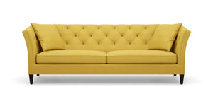 The Shelton 98" Sofa features a tufted backrest and two seat cushions in a mustard yellow color. It is designed with flair arms and rests on dark wooden legs.
