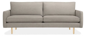 The 86" Jasper Sofa is a modern piece in grey with sleek, straight lines and wooden legs. It includes two large backrest cushions and two seat cushions, presenting a minimalist and contemporary design.