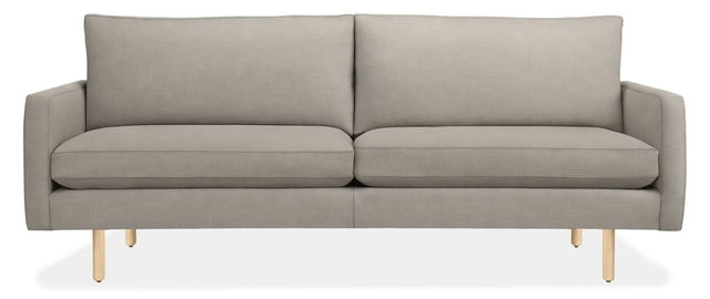 The 86" Jasper Sofa is a modern piece in grey with sleek, straight lines and wooden legs. It includes two large backrest cushions and two seat cushions, presenting a minimalist and contemporary design.