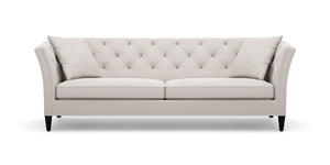 The Shelton 98" Sofa is a modern piece with a light grey finish, tufted design, and sloped arms paired with black legs. It includes two matching cushions, and its clean lines along with the neutral color contribute to its elegance and versatility in complementing various interior styles.