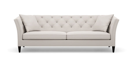 The Shelton 98" Sofa is a modern piece with a light grey finish, tufted design, and sloped arms paired with black legs. It includes two matching cushions, and its clean lines along with the neutral color contribute to its elegance and versatility in complementing various interior styles.