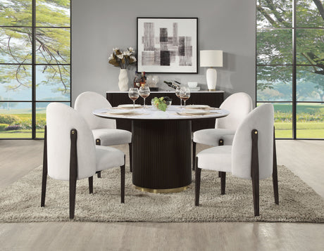 A modern dining room features the Clayten Around Dining Table in marble/espresso, set for four with white upholstered chairs on a textured rug. Large windows showcase a lush view, accompanied by abstract art on minimalist walls and a sideboard adorned with additional decor.