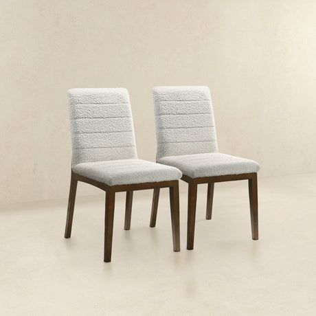 The Ines Modern Dining Chairs, set of 2, feature light-colored fabric upholstery and dark wooden legs. Arranged side by side against a beige background, they showcase a sleek design with horizontally stitched patterns on the backrest.