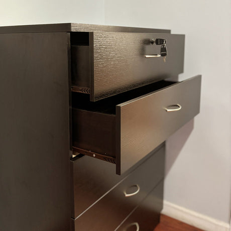 A 5 Drawer Chest with a melamine laminate and metal handles stands on a hardwood floor against a plain wall. The top drawer, equipped with metal glide rails and a locking mechanism, is slightly open with a key inserted, while the other three drawers remain closed.