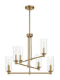 The Timeless chandelier showcases a modern, linear design with a gold finish and features six clear ribbed satin cylindrical glass shades. It is suspended from an antique brass matching rod with a round ceiling mount.
