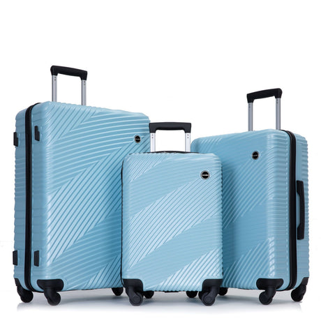 Three blue suitcases with diagonal stripes, each featuring a telescopic handle and spinner wheels, stand on the floor. The largest suitcase is on the left and the smallest in the center.