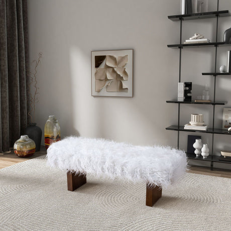 A room showcases the Henley - Fur Bench in white khaki with wooden legs on a patterned rug. A geometric artwork adorns the wall, and a black shelving unit holds decor items alongside large ceramic vases and a dark curtain.