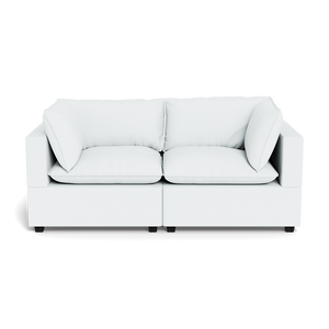 The Kova Pillow Cushion Sofa 86" is a modern white sofa featuring two seat cushions, two back cushions, and four side pillows, shown from the front against a black background.