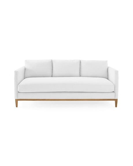 The Barton Sofa is a modern white piece featuring three cushions set against a clean, white background. It boasts a minimalist design with wooden legs, offering a stylish and contemporary look.