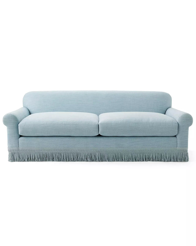 The Cambridge Sofa in Washed Linen is a light blue upholstered piece with a classic design, featuring rolled arms and a skirted fringe at the bottom for a traditional and elegant look. It includes two seat cushions and a smooth backrest.