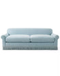 The Cambridge Sofa in Washed Linen is a light blue upholstered piece with a classic design, featuring rolled arms and a skirted fringe at the bottom for a traditional and elegant look. It includes two seat cushions and a smooth backrest.