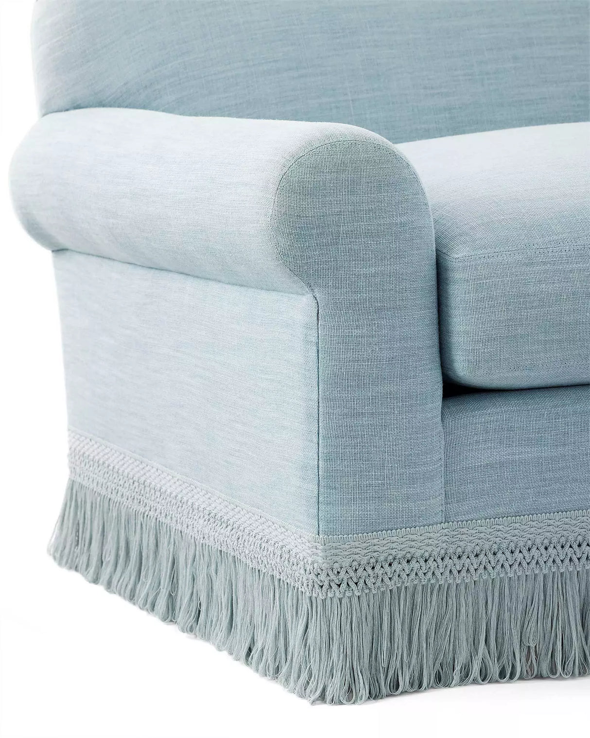 Close-up of the Cambridge Sofa in washed linen, featuring a light blue upholstery with rolled armrests and decorative fringe at the bottom. The fabric exhibits a soft, textured appearance, enhancing the sofa's elegant and classic look.