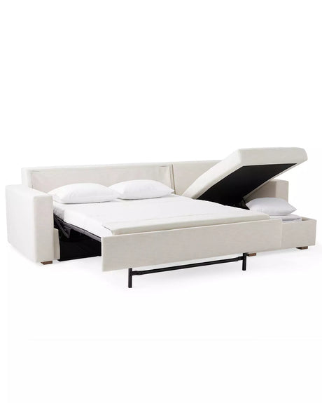 Image of the Conover Sleeper Chaise Sectional in white, showcasing a pull-out bed and a storage compartment. The sectional features two pillows and boasts a sleek, modern design with a minimalist aesthetic. The lid of the storage compartment is partially open, revealing additional space.