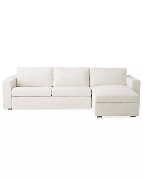 The Conover Sleeper Chaise Sectional is a light beige sofa featuring three cushions and a right-side chaise. It is designed with wide armrests and short wooden legs, showcased against a plain white background.