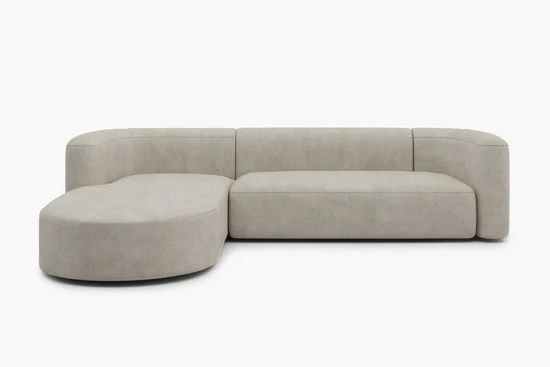 The Mellow Sectional Sofa by Acanva is a modern, beige sofa featuring a rounded chaise lounge on the left side. Presented against a white background, this piece boasts a minimalist and elegant design with clean lines and a smooth texture.