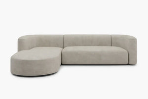The Mellow Sectional Sofa by Acanva is a modern, beige sofa featuring a rounded chaise lounge on the left side. Presented against a white background, this piece boasts a minimalist and elegant design with clean lines and a smooth texture.