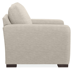 Side view of the Metro Sofas with Chaise, showcasing a modern beige fabric design characterized by clean lines and a blocky structure. This sofa features a tall backrest and armrest, and is supported by dark wooden legs, against a plain white background.