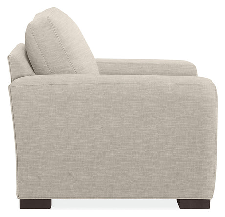 Side view of the Metro Sofas with Chaise, showcasing a modern beige fabric design characterized by clean lines and a blocky structure. This sofa features a tall backrest and armrest, and is supported by dark wooden legs, against a plain white background.