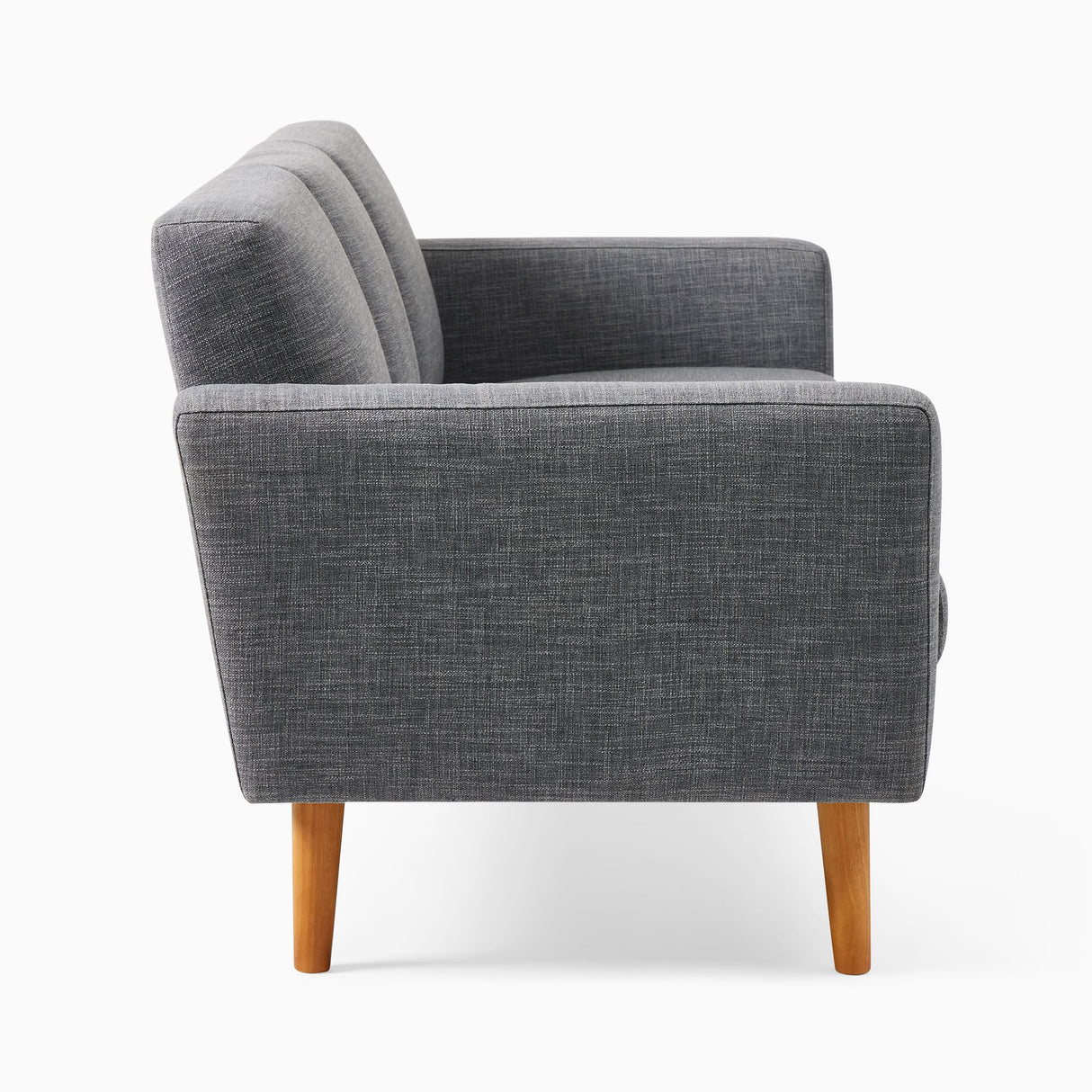 Side view of the Oliver Sofa, a modern gray upholstered piece with wooden legs. It boasts a sleek design with stitched detailing on the backrest and armrests, offering a contemporary and minimalist appearance.