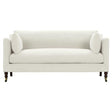 The Madeline French Grey Upholstered Brown Wood Brass Casters Nailhead Sofa Large is a contemporary masterpiece in white, featuring clean lines and two matching bolster pillows. It boasts elegant wooden legs with brass casters that add a sophisticated touch to its sleek, minimalistic design.