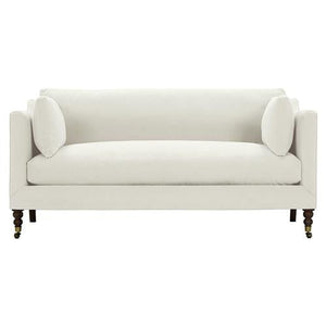 The Madeline French Grey Upholstered Brown Wood Brass Casters Nailhead Sofa Large is a contemporary masterpiece in white, featuring clean lines and two matching bolster pillows. It boasts elegant wooden legs with brass casters that add a sophisticated touch to its sleek, minimalistic design.