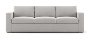 The Rio Sofa is a light gray three-seater with plush cushions and wide armrests, set against a white background with simple, modern design elements.