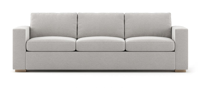 The Rio Sofa is a light gray three-seater with plush cushions and wide armrests, set against a white background with simple, modern design elements.